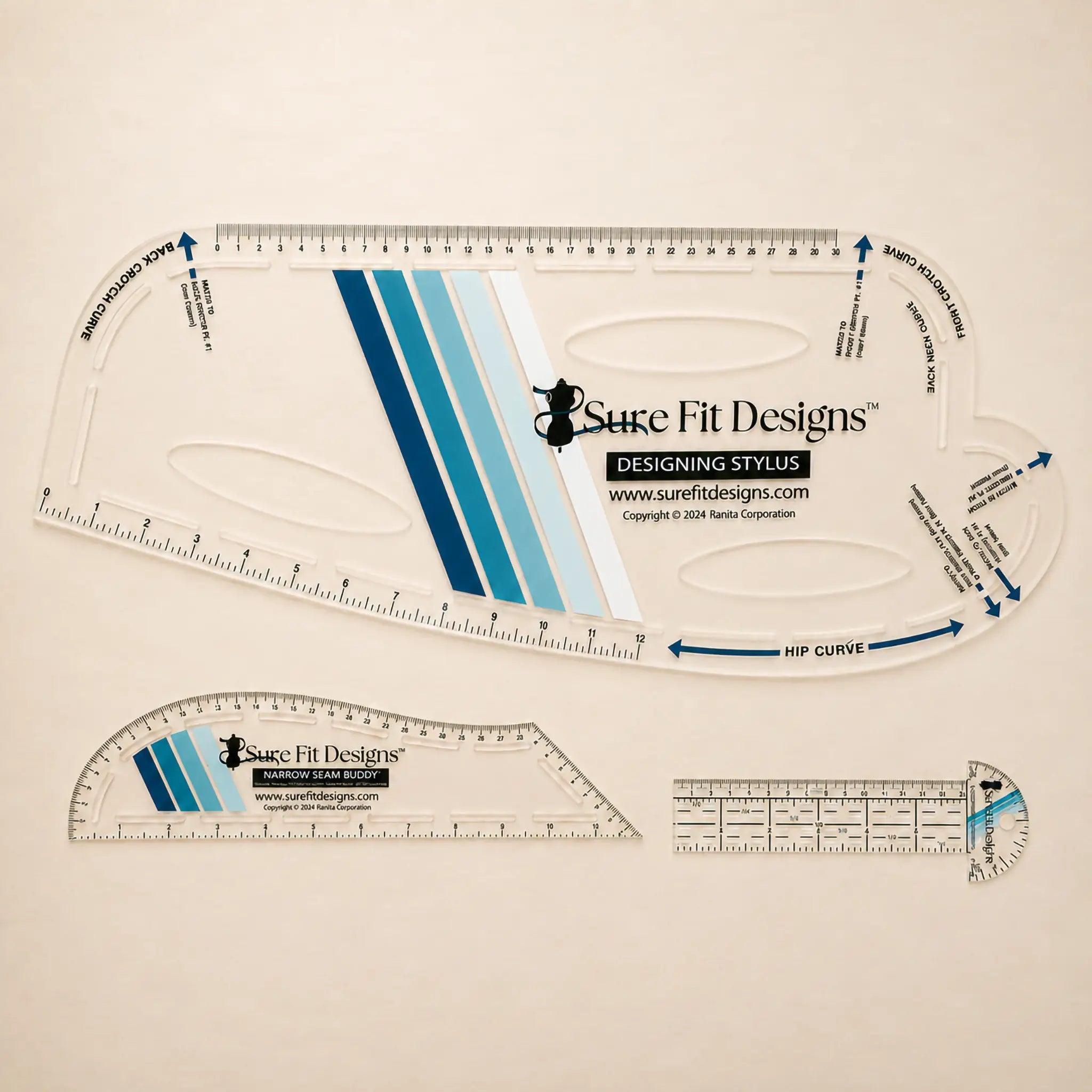 A collection of three Sure Fit Designs tools for patternmaking, a Designing Stylus, a Narrow Seam Buddy and a Curved T Square on a pale maple table