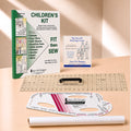 A children's sewing kit laid out on a light wood surface, including a green and white instruction booklet, a small blue-and-white guide card, a clear gridded quilting ruler, a white curved measuring template, and a rolled white paper sheet. Visible branding includes Sure Fit Designs and The Save Fit Designs.