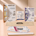 A sewing and measurement kit set displayed on a beige surface, including a 'PANTS KIT' manual, 'MEN'S PANTS INSTRUCTIONAL PACKAGE', a clear marked square grid, a black rotary cutter, a white and pink curved measuring template, and a white roll of paper. The brand 'Sure Fit Designs' is clearly visible on the manuals and tools.