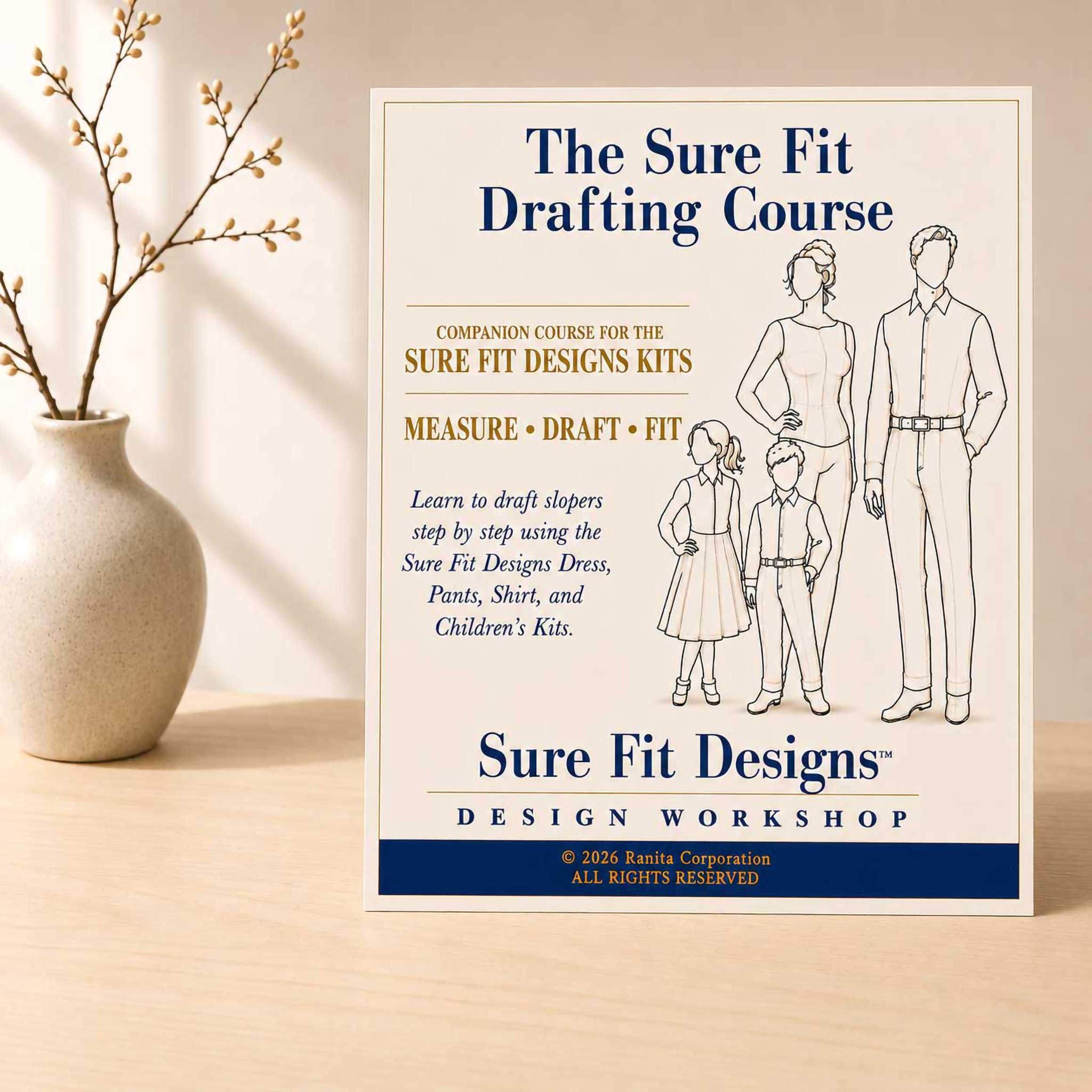 The Sure Fit Drafting Course displayed vertically on a light maple table with a small flower arrangement on the left
